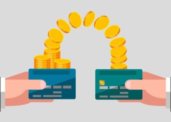 Male hands are keeping bank cards. Gold coins from one card are moving to another card. Money transfer. Business concept