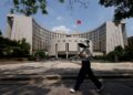 FILE PHOTO: A person walks past the headquarters of the People's Bank of China, in Beijing, China May 7, 2025. REUTERS/Tingshu Wang/ File Photo