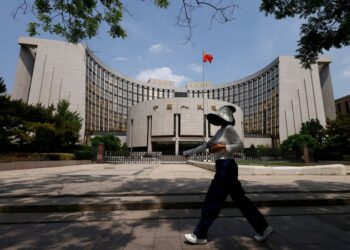 FILE PHOTO: A person walks past the headquarters of the People's Bank of China, in Beijing, China May 7, 2025. REUTERS/Tingshu Wang/ File Photo