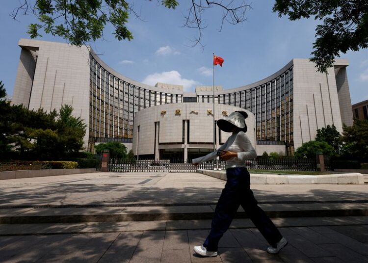FILE PHOTO: A person walks past the headquarters of the People's Bank of China, in Beijing, China May 7, 2025. REUTERS/Tingshu Wang/ File Photo